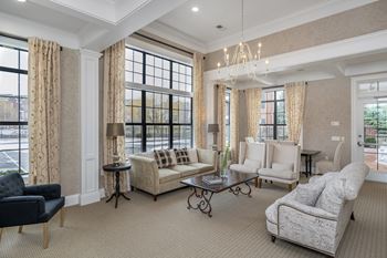 A living room with a black chair, a white sofa, and a chandelier.